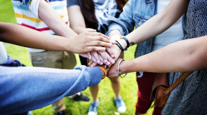 A group of people standing in a circle putting their hands together in the middle